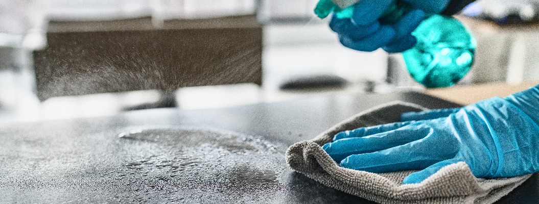 Desinfizierung von Oberflächen Reinigung des Küchentischs mit Desinfektionsmittel Sprühflasche Waschen der Oberfläche mit Handtuch und Handschuhen. COVID-19 Prävention Desinfektion innen.